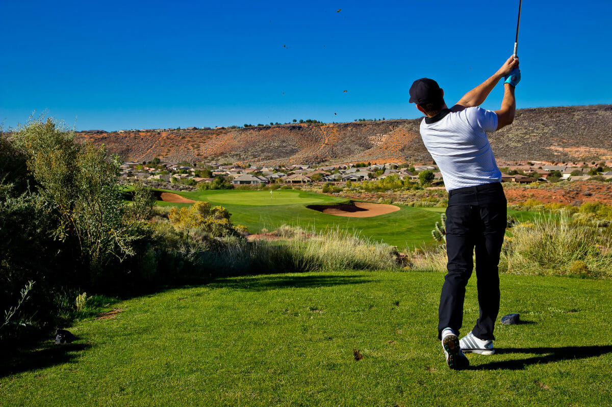 View from behind of a male golfer in mid swing.