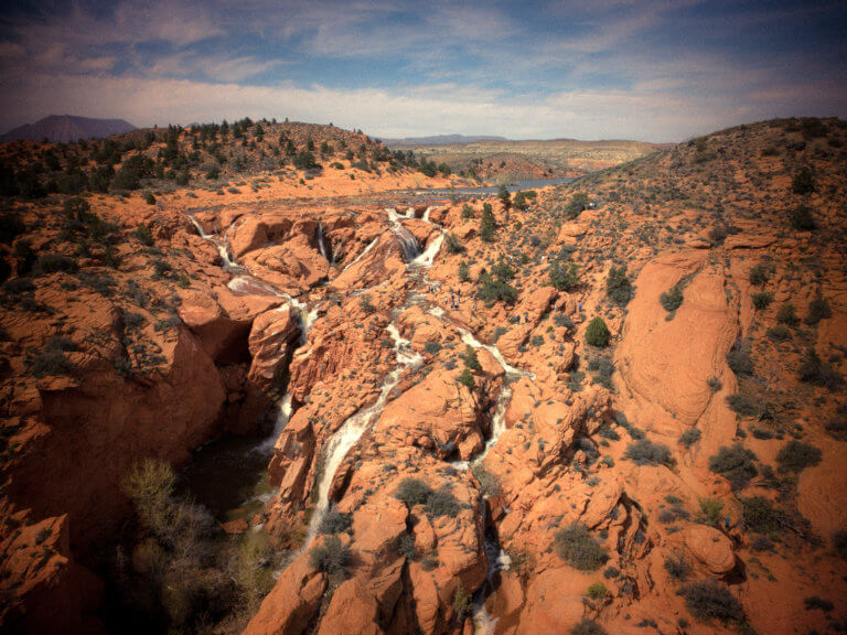 Water flowing from desert reservoir through rugged red rock formations