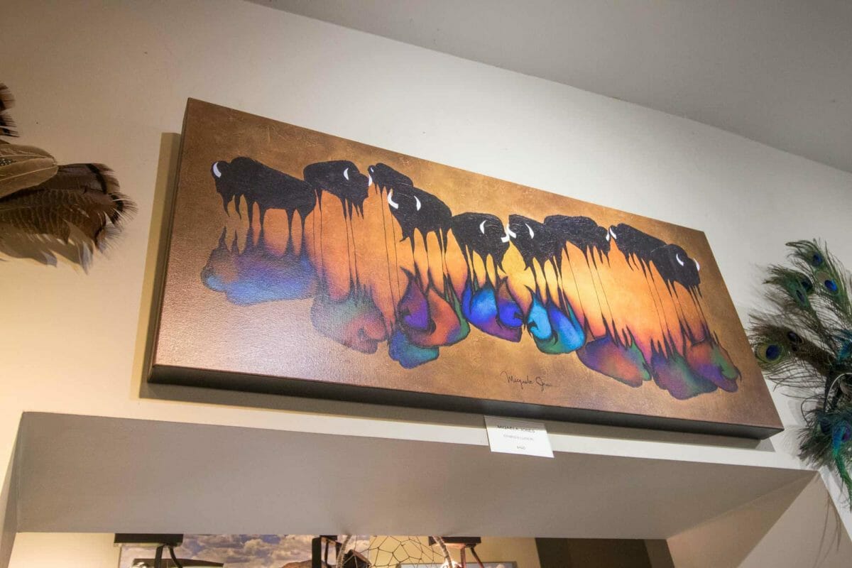 Painting of buffalo hanging on gallery wall.