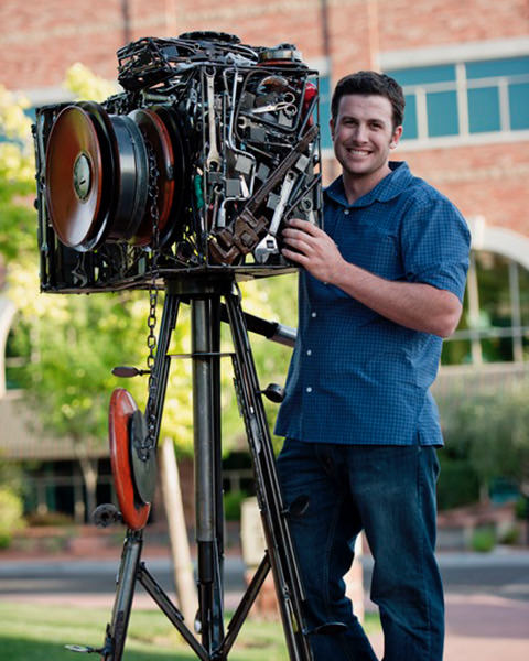 Photographer standing next to sculpture of a camera.