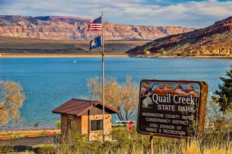 Entrance sign in front of lake reading Quail Creek State Park