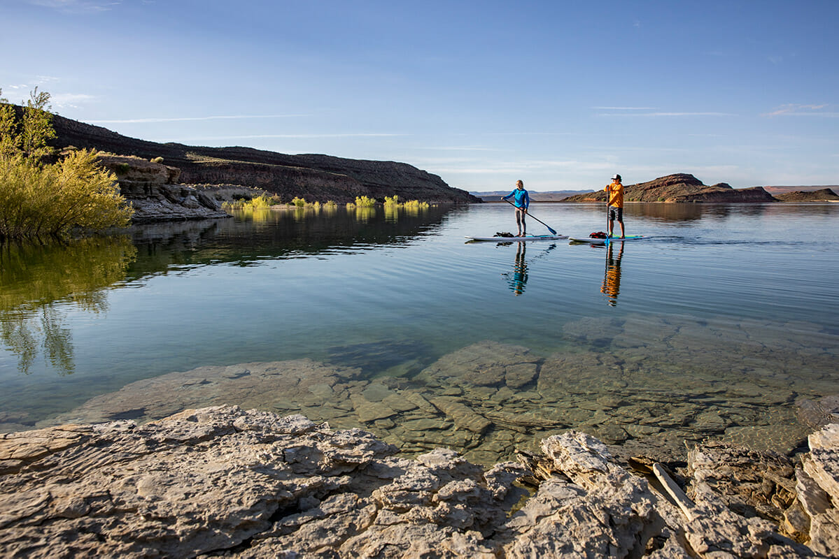 Couple paddleboarding on still lake