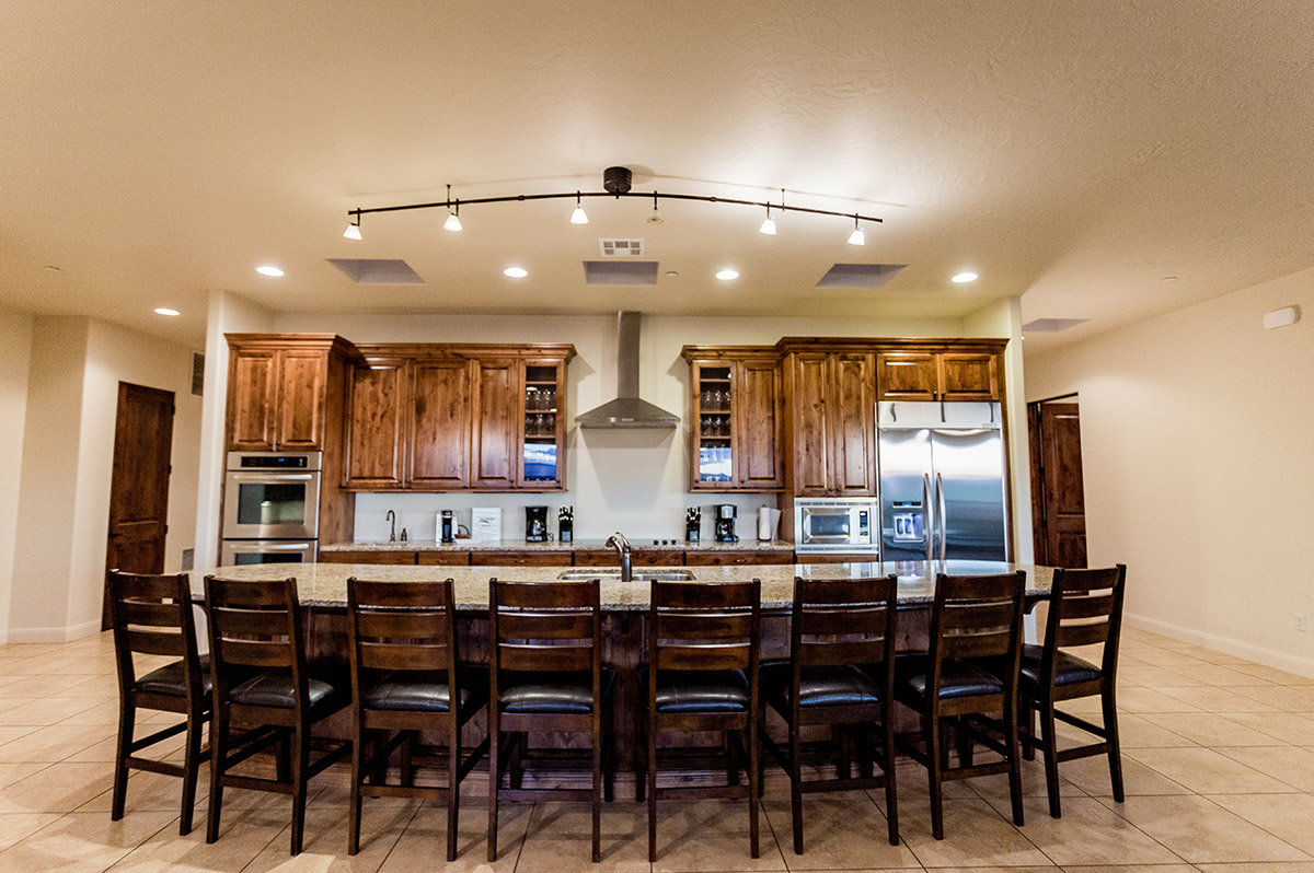 Hotel suite kitchen with eight barstools lined up at granite counter top