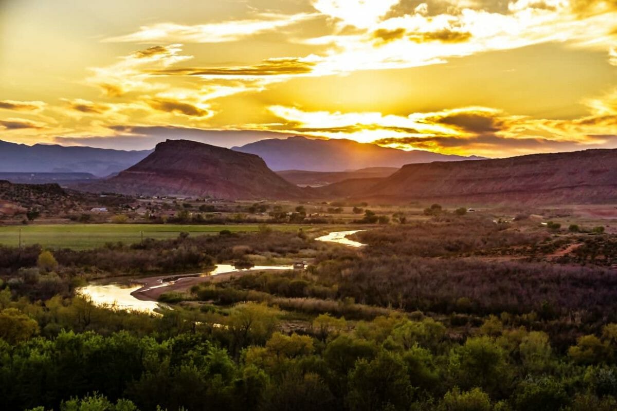 Sun rising over mountains and reflecting off of winding river.